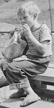 Child of miner eating lunch on schoolhouse grounds.